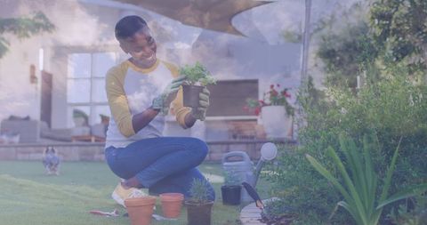 Kneeling woman planting seedlings in backyard with gloves, watering can and pots