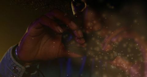 Closeup indian musician playing harmonica with denim sleeve rimlight and dust particles