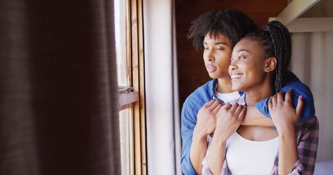 Affectionate couple gazing out rustic cabin window