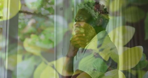 Pensive African American Man Peering Through Bright Foliage