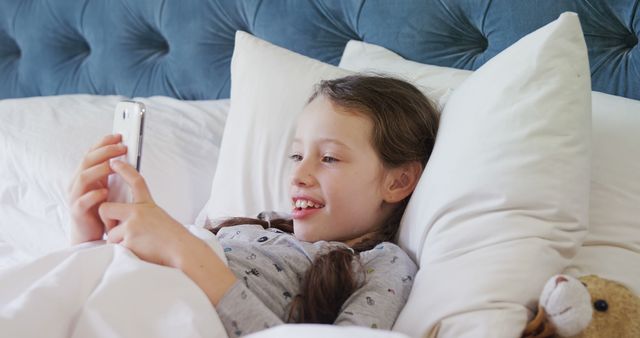 Young Girl Lying in Bed Smiling at Smartphone Screen - Download Free Stock Images Pikwizard.com