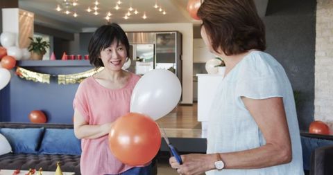 Senior Friends Preparing Birthday Party Decorations in Living Room