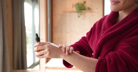 Woman practicing skincare ritual with serum in cozy home