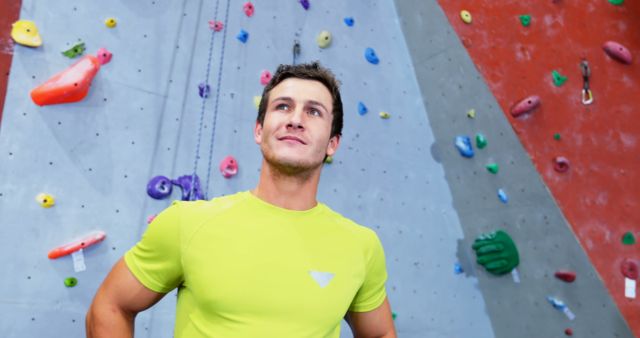 Confident Man in Green Shirt Standing at Indoor Rock Climbing Gym - Download Free Stock Images Pikwizard.com