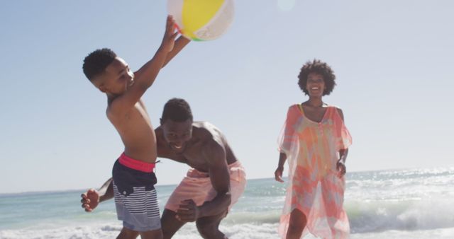 Smiling african american family playing with ball on sunny beach - Download Free Stock Photos Pikwizard.com