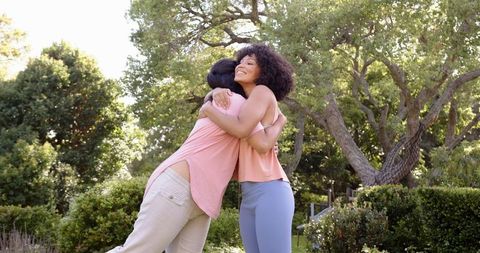 Mother and Daughter Hugging in Park Surrounded by Nature