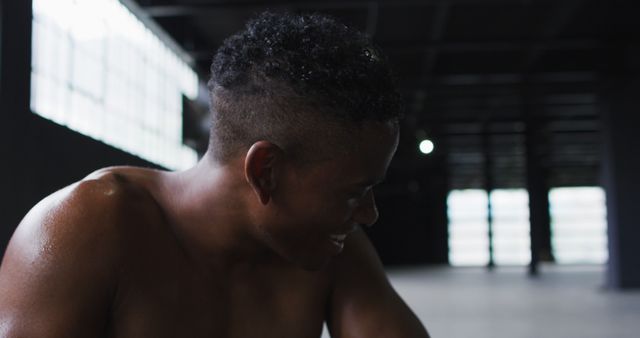 Young man with a smiling, sweaty face, likely post-workout, in the gym. Suitable for use in fitness blogs, exercise motivation articles, gym advertisements, and health lifestyle promotions.