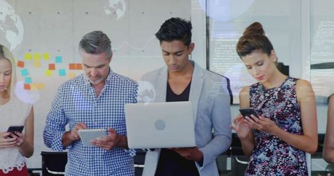 Colleagues collaborating using smartphones tablet and laptop in modern office