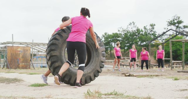 Diverse group of happy female friends cross training outdoors, lifting truck tyre. Female fitness, challenge and healthy lifestyle.