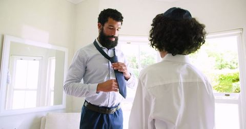 Father teaches son how to tie tie for special occasion