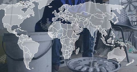 Mechanic rinsing alloy wheel rim in garage workshop with bucket water and map overlay