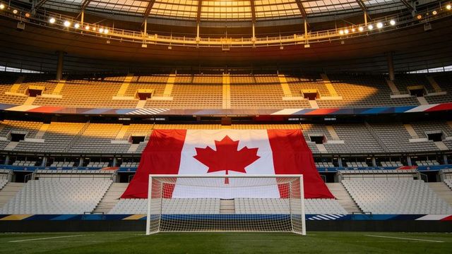 Massive canadian flag draping over central stands behind soccer goal at sunset light
