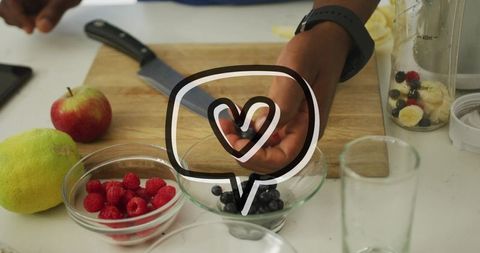 Preparing fresh berries for smoothie on wooden cutting board with knife and blender jar