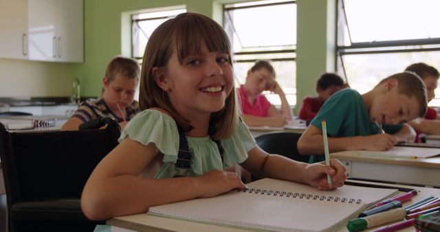 Smiling Girl Completing Schoolwork in Classroom with Classmates - Download Free Stock Images Pikwizard.com