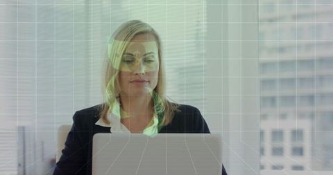 Businesswoman typing on laptop with holographic financial interface and grid overlay