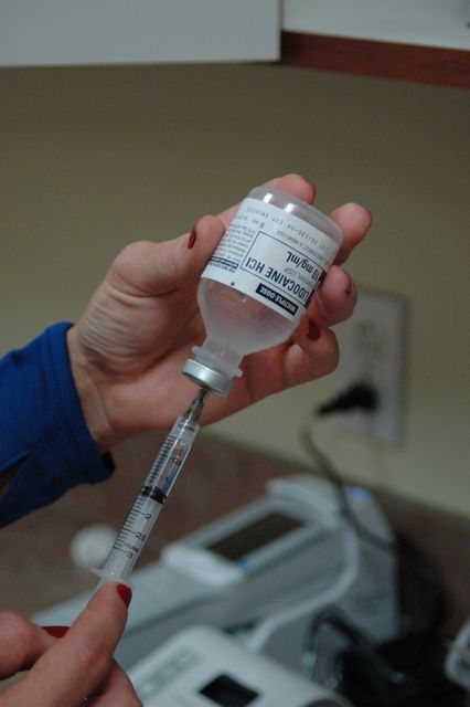 Shows healthcare professional preparing syringe with medication in medical environment. Ideal for use in medical articles, healthcare materials, vaccination campaigns, or patient education resources.