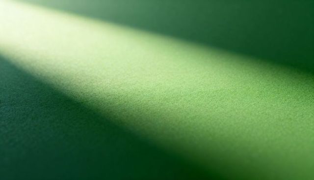 Diagonal light creating textured emerald surface with soft gradient and deep shadow, minimal feel