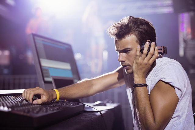 Young male DJ mixing music at a nightclub during a music festival. Ideal for use in promotions for nightlife events, music festivals, DJ performances, and entertainment industry advertisements.