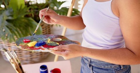 Woman artist with paint palette creating vibrant artwork outdoors