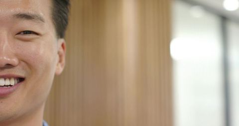 Smiling asian man closeup in modern office copy space for corporate branding and marketing