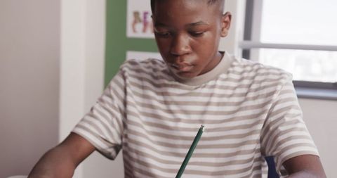 Focused african american student writing at classroom desk