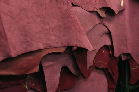 Stacks of maroon leather hides awaiting craftsmanship