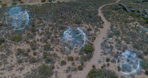 Aerial desert mapping with holographic geospatial orbs hovering over winding dirt trail