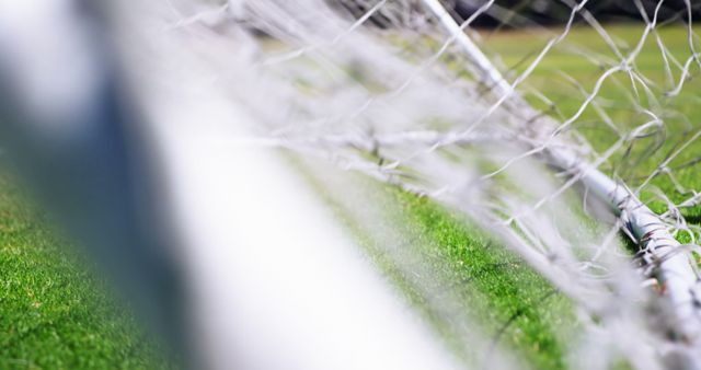 A close-up view of a soccer goal net with a blurred background, with copy space. Focus on the mesh pattern emphasizes the sport's theme and provides a backdrop for soccer-related content.