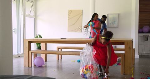 Family cleaning up party decorations together at home