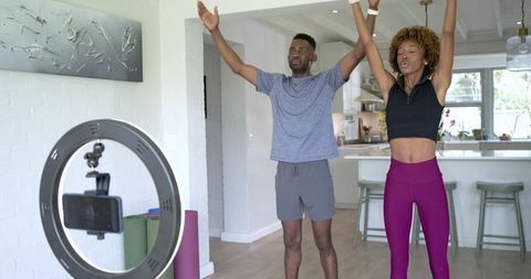 Couple recording workout with led ring light and smartphone in open-plan kitchen