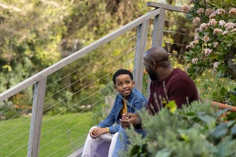 African american father and son sharing conversation on backyard deck with cable railing