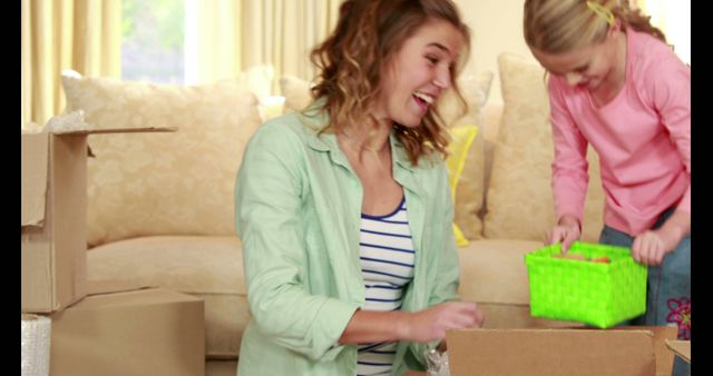 Laughing mother and daughter unpacking boxes in new home - Download Free Stock Images Pikwizard.com