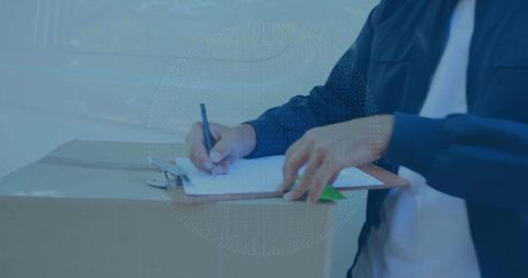 Delivery man signing on cardboard box next to van