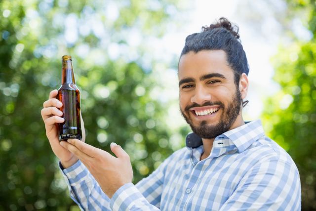 Man holding beer bottle in the park on a sunny day