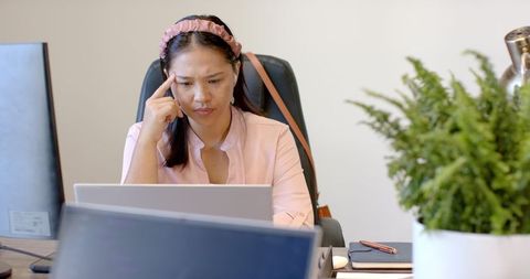 Woman Focusing on Laptop in Office Environment