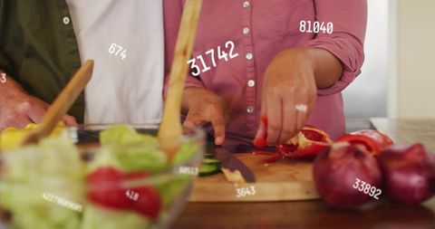 Couple chopping vegetables together in cozy kitchen with digital data overlay graphics