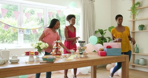 Women Preparing Baby Shower Celebration with Desserts and Gifts