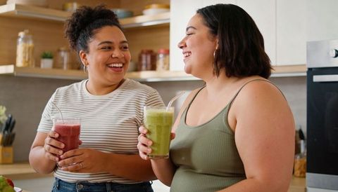 Friends enjoying healthy smoothies in bright home kitchen sharing laughter and morning wellness