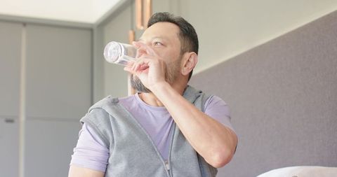Middle-aged asian man enjoying drink at home