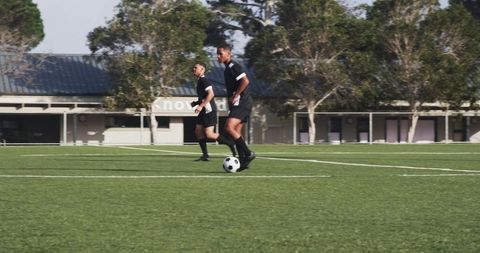 Two soccer players running with ball on field
