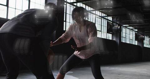 Backlit athletic partners sparring in industrial warehouse with digital projection