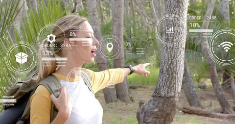 Woman hiker pointing and scanning forest with ar hud wearing backpack and smartwatch