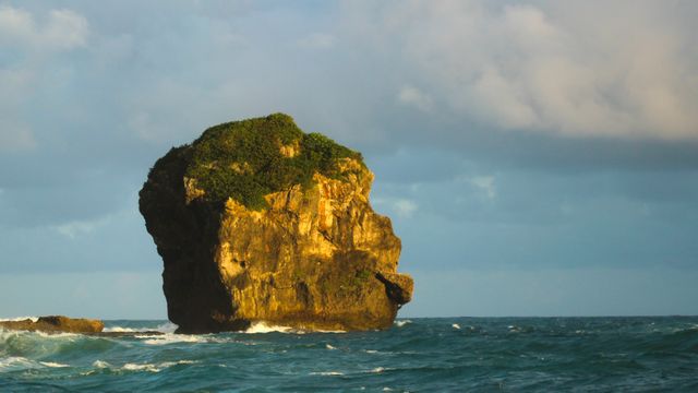 Capturing a stunning moment, this majestic rock formation rises from the ocean as the sun begins to set. Suitable for travel blogs, nature articles, and scenic backgrounds. Ideal for promoting coastal tourism, environmental conservation, and peaceful getaways.