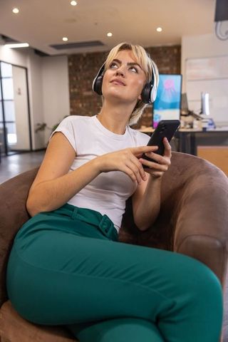 Woman Relaxing in Office Lounge with Headphones and Smartphone