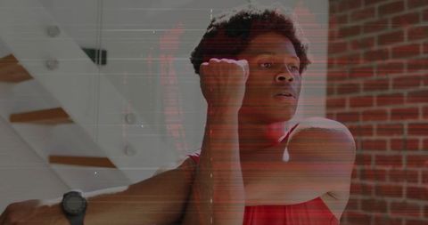 Man stretching arm across chest wearing smartwatch and red tank top in urban interior