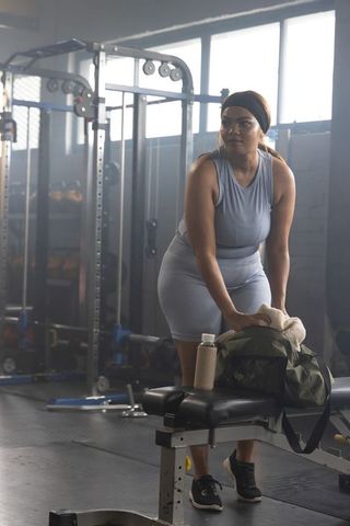 African american woman adjusting gym bag on bench during strength training session