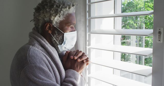 Elderly Man in Mask Standing by Window Reflecting - Download Free Stock Images Pikwizard.com