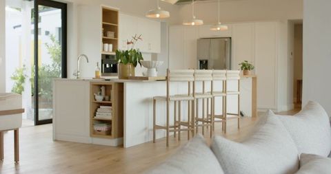 Bright scandinavian open-plan kitchen with white island, wood countertop and woven stools