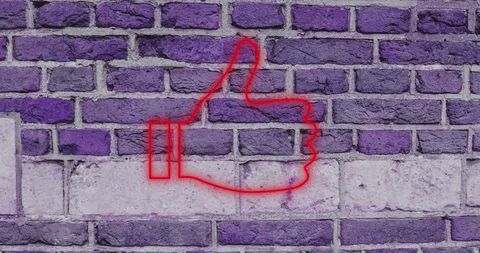 Red Neon Thumbs Up on Purple Brick Wall Creating Bold Contrast