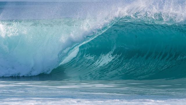 Curling Teal Barrel Wave Breaking at Shoreline with Foam Spray and Turquoise Sea